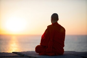 Buddhist Monk Meditating at Sunset on Beach