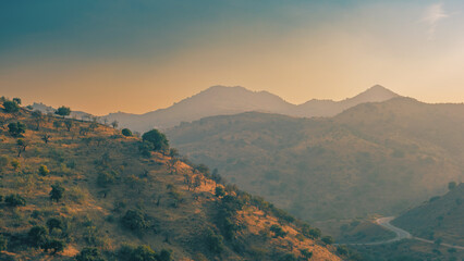 Hazy valley with hills and olive trees during sunset. Almogia, Malaga, Andalucia, Spain.