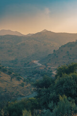 Hazy valley with hills and olive trees during sunset. Almogia, Malaga, Andalucia, Spain.