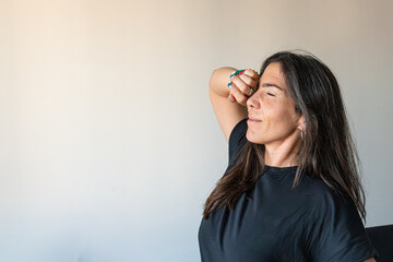 Fototapeta premium Woman with closed eyes and arm over forehead finding a moment of comfort