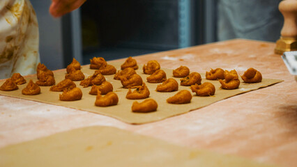Artisan hands preparing traditional fresh tortelloni pasta, placing pumpkin filling onto dough, crafting Italian savory food for an authentic culinary experience