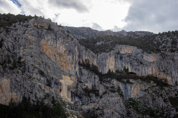 Layered rocky canyon wall under dramatic cloudy sky