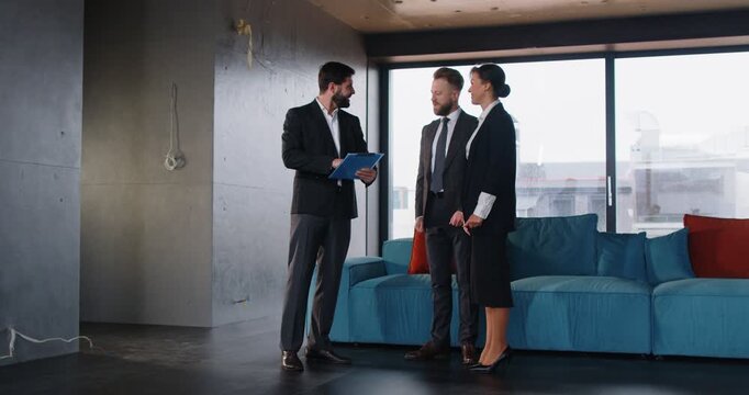 Professional realtor exchanging handshake with clients, greeting potential buyers at construction site of modern office. Real estate agent presenting space for purchase or rent to business people.