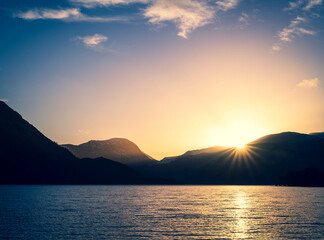 Golden sunset over Ullswater with mountain silhouettes in the Lake District.