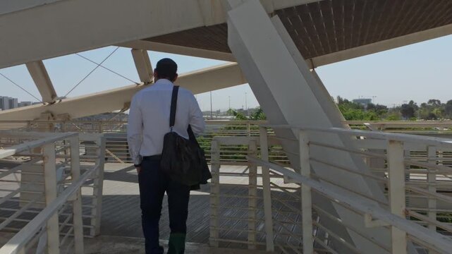 Jewish Businessman Wearing a Kippah and Using a Smartphone on a Modern Bridge