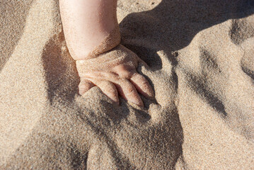 Little baby hand playing in beach sand