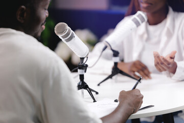 Two african adults peoples recording podcast studio with microphones and notes, banner