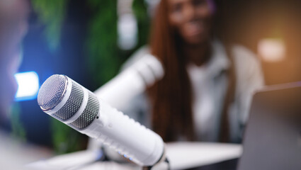 Close-up of white microphone in podcast setting with blurred background, banner with sunlight