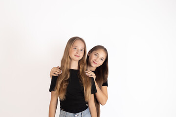 Two teenage girls hugging and smiling in a studio setting. Fun, positive