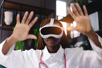 African female doctor using virtual reality headset in modern clinic, sunlight