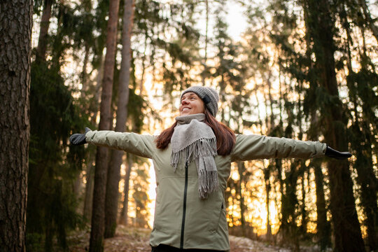 Fototapeta Woman in forest in winter. Happy in nature in Finland. Trees in woods. Healthy Finnish outdoor lifestyle. Smiling person arms raised. Fresh air.