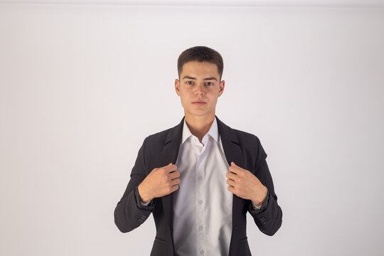 Young man adjusting his tie while posing in a white studio
