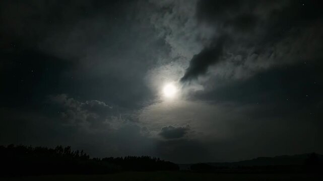 Nighttime landscape featuring a glowing full moon partially obscured by clouds surrounded by a dark sky filled with stars and distant mountains highlighting the tranquil nature setting