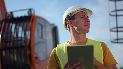 Worker uses tablet for inspection on construction site wearing helmet and safety vest near crane engineer checking data on tablet technology supporting onsite inspection construction safety management - Powered by Adobe