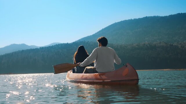A couple celebrates in a canoe on a serene lake, surrounded by mountains. They raise their paddles triumphantly, symbolizing joy and adventure.