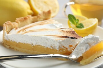 Slice of tasty lemon meringue tart with mint served on table, closeup