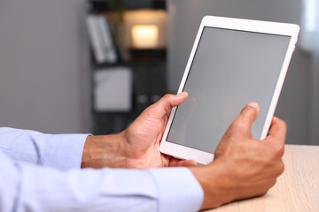 African-american man using tablet at wooden table indoors, closeup