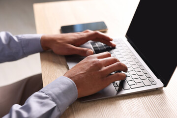 African-american man using laptop at wooden table indoors, closeup
