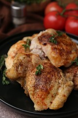 Tasty cooked chicken thighs with thyme and tomatoes on table, closeup