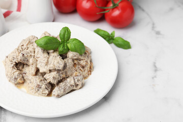 Tasty beef Stroganoff with basil and tomatoes on white marble table, closeup. Space for text