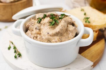 Tasty beef Stroganoff with thyme in casserole and bread on table, closeup