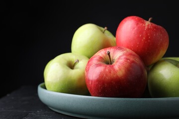 Fresh red and green apples on dark textured table against black background, closeup