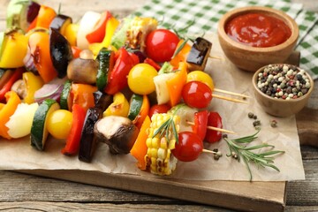 Skewers with tasty grilled vegetables, sauce and peppercorns on wooden table, closeup