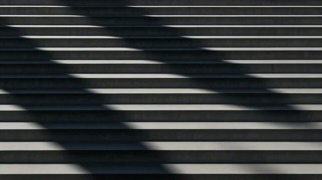 Close-up view of concrete stairs showcasing harmonious geometric patterns emphasizing shadows and light play against a gray and black backdrop in a well-lit urban environment