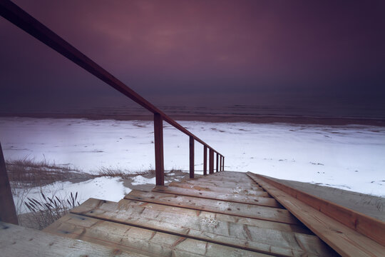 Vibrant Baltic Sea Winter Sunset with wooden ladders pathway to the sandy beach in Lithuania - Powered by Adobe