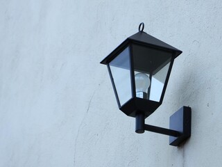 A black flashlight hangs on the light wall of the house, like the one at the entrance.