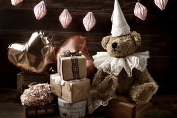 Vintage style teddy bear in lace ruff collar and a cap at a birthday party in sepia color