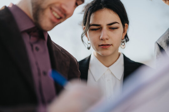 A small group of colleagues gathers outside, focused on a document review. - Powered by Adobe