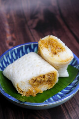 A closeup shot of a traditional Goan Alle Belle coconut pancakes. The crepes are rolled neatly and filled with a rich, dark brown mixture of grated coconut and palm jaggery. popular tea time snack.