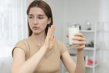 women refusing glass of milk, showing signs of lactose intolerance or dairy allergy, expressing discomfort, dietary restriction, health related food avoidance.
