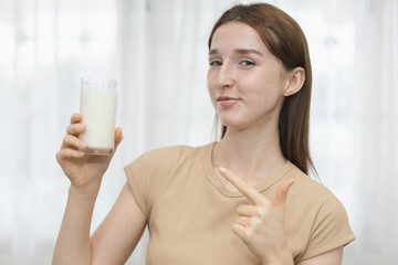 women pointing at a glass of milk, promoting healthy nutrition, calcium rich drink and benefits of daily dairy consumption for strong bones and wellness.