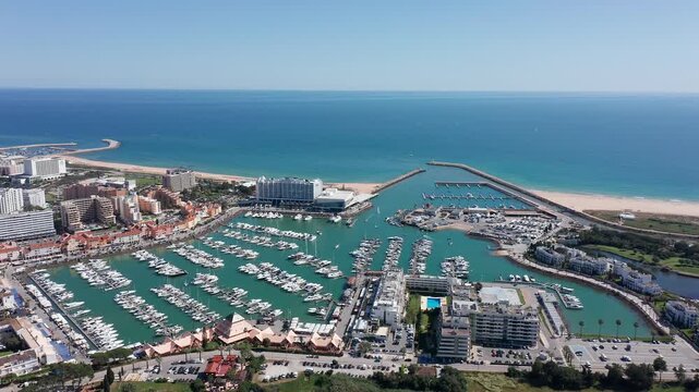 Vilamoura aerial view aerial view protected bay vilamoura with curved breakwater arc sheltering busy marina, turquoise lagoon, coastal hotels and beach, calm summer atmosphere