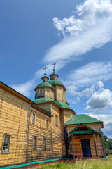 Green summer colors light up the countryside among old wooden houses and ancient churches in Ukraine, creating a warm nostalgic atmosphere.
