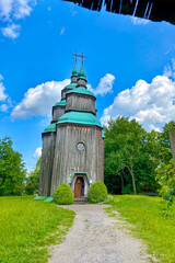 Green summer colors light up the countryside among old wooden houses and ancient churches in Ukraine, creating a warm nostalgic atmosphere.

