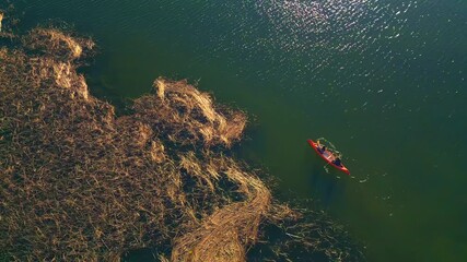 A lone canoe glides through calm waters, surrounded by dense, dry reeds. The scene captures a serene moment of solitude and exploration, ideal for canoeing enthusiasts seeking a peaceful escape.