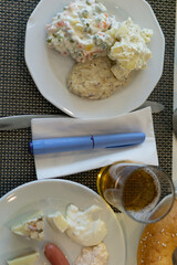 close up of a blue medication injection pen Ozempic for diabetes or weight loss placed on a napkin on a breakfast or buffet table next to two plates of food