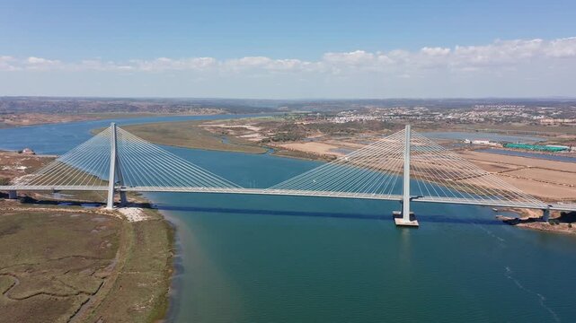 Ponte internacional Guadiana wide aerial view of bridge spain, full-length cable-stayed structure crossing guadiana estuary, turquoise channel, adjacent salt flats and urban fringe, visible