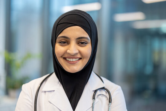Muslim woman doctor wearing a hijab and stethoscope. Smiling confidently at the camera. Symbolizing professionalism. Dedication. Inclusive healthcare. And patient care in a modern medical environment