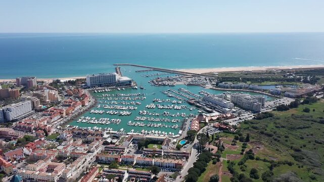 Vilamoura aerial view aerial wide coastal view vilamoura showing expansive marina basin, long sandy beaches, protective breakwaters and green parkland, calm sea and panoramic horizon