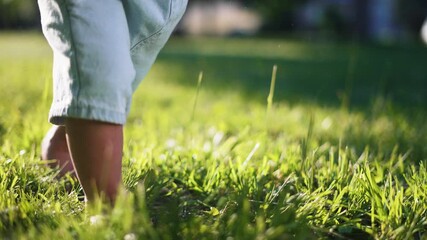 Toddler walking on grass barefoot baby leg and child step captured in sunlight on green lawn near backyard closeup of foot toe touching grass joyful play and first step exploration under warm sunlight