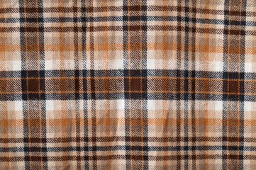Plaid brown orange beige flannel cotton fabric, tartan pattern. Close-up of this autumnal natural fabric for shirt, dress, tablecloth, or clothing. Abstract textile background, backdrop, wallpaper.