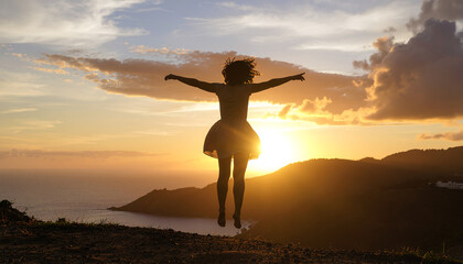 Joyful silhouette jumping against vibrant sunset over ocean vista, arms wide open, symbolizing freedom, happiness, and success.