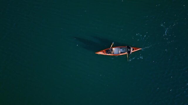 A couple paddles a canoe on calm, deep blue waters, embodying a serene weekend activity. Their synchronized strokes reflect teamwork, captured with drone footage.