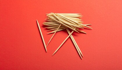 Scattered wooden toothpicks on vibrant red surface with clustered and parallel arrangement