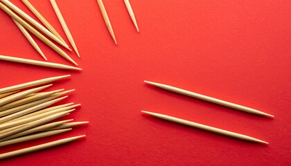 Scattered wooden toothpicks on vibrant red surface with clustered and parallel arrangement
