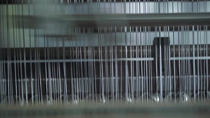 Industrial loom operating with synchronized needle movement, factory scene showcasing rapid weaving machine producing patterned textiles with rhythmic motion
